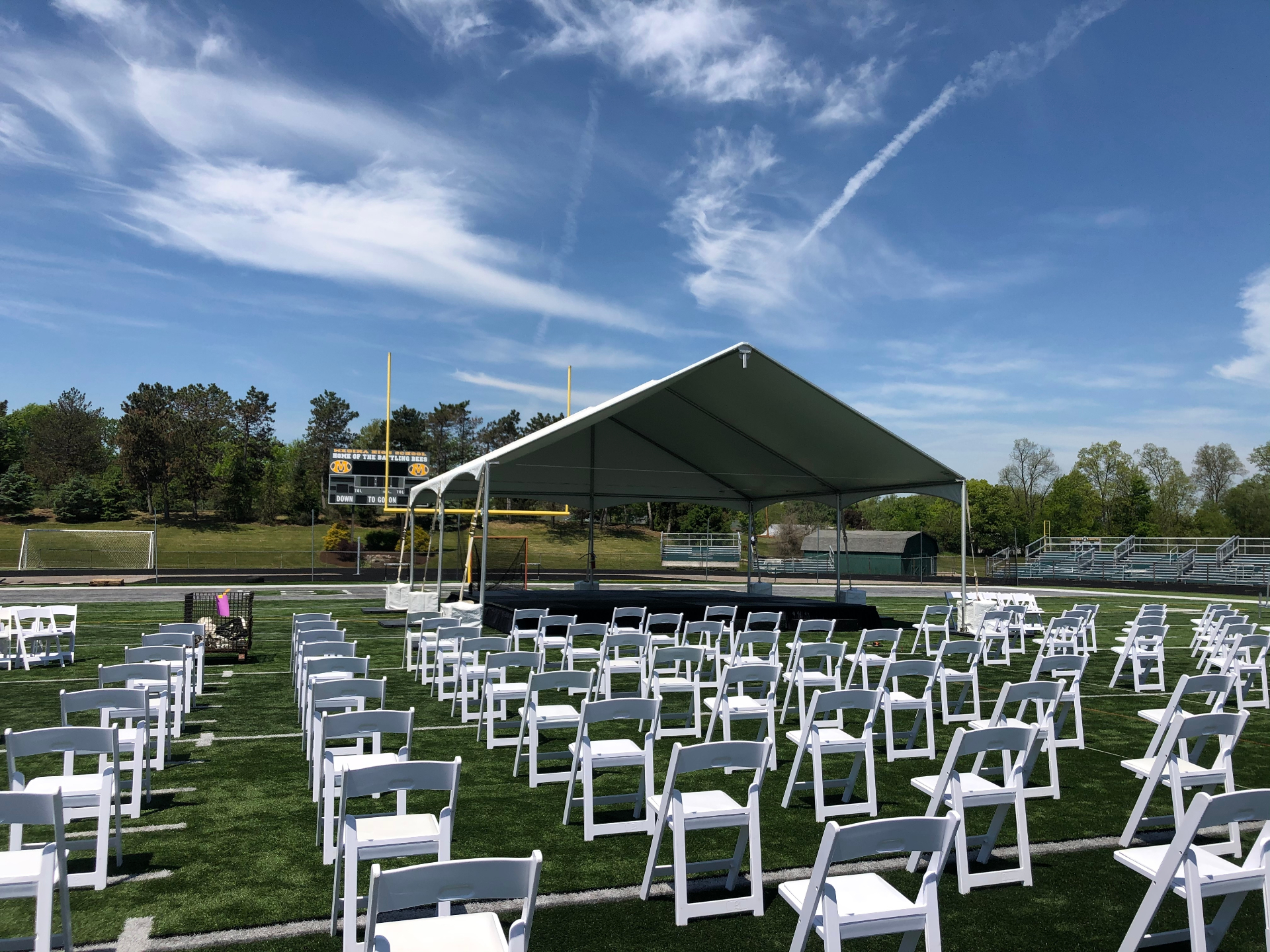 Athletic field graduation ceremony with stage and seating